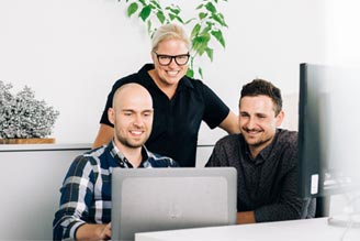 Drei GRATZ Mitarbeiter schauen in einen Laptop
