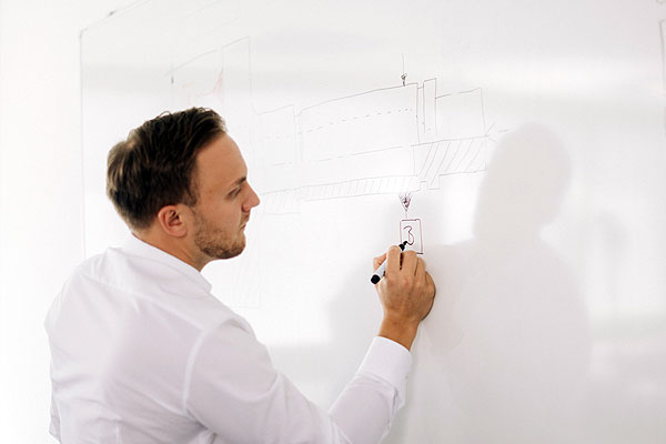 Ingenieur skizziert auf einem Whiteboard.